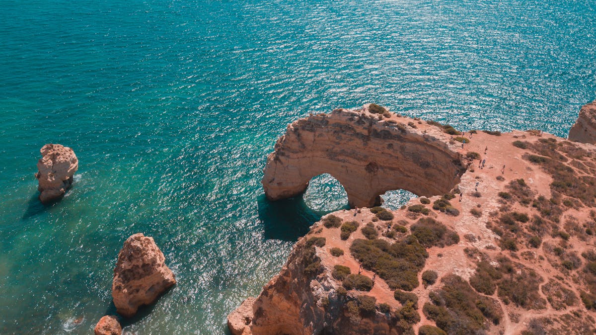 Aerial view of the natural rock arch and turquoise water at Praia da Marinha in the Algarve