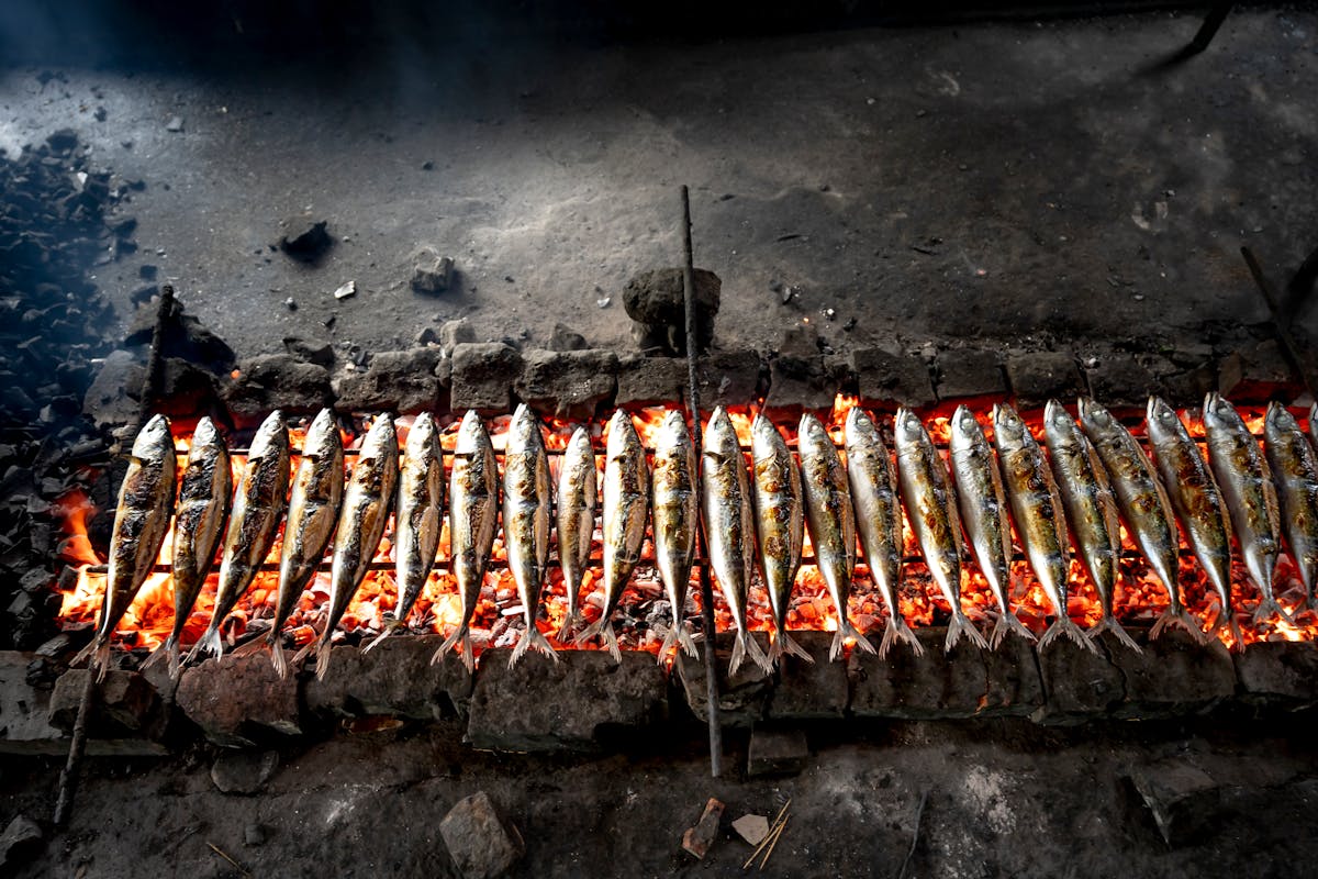 Sardines grilling over charcoal, a classic Algarve dish