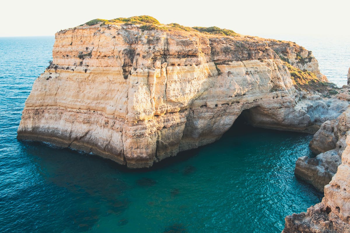 Golden limestone sea stack in turquoise water on the Algarve coast at golden hour