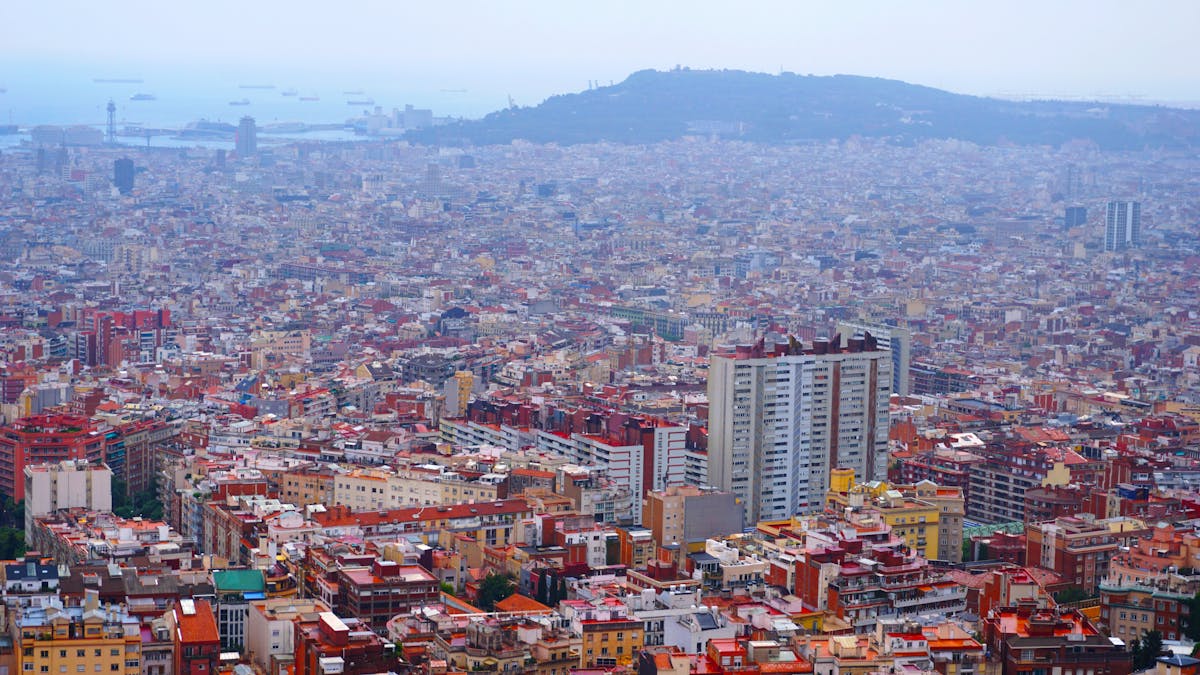 Aerial panoramic view of Barcelona's distinctive urban grid and the coastline beyond, Catalonia, Spain
