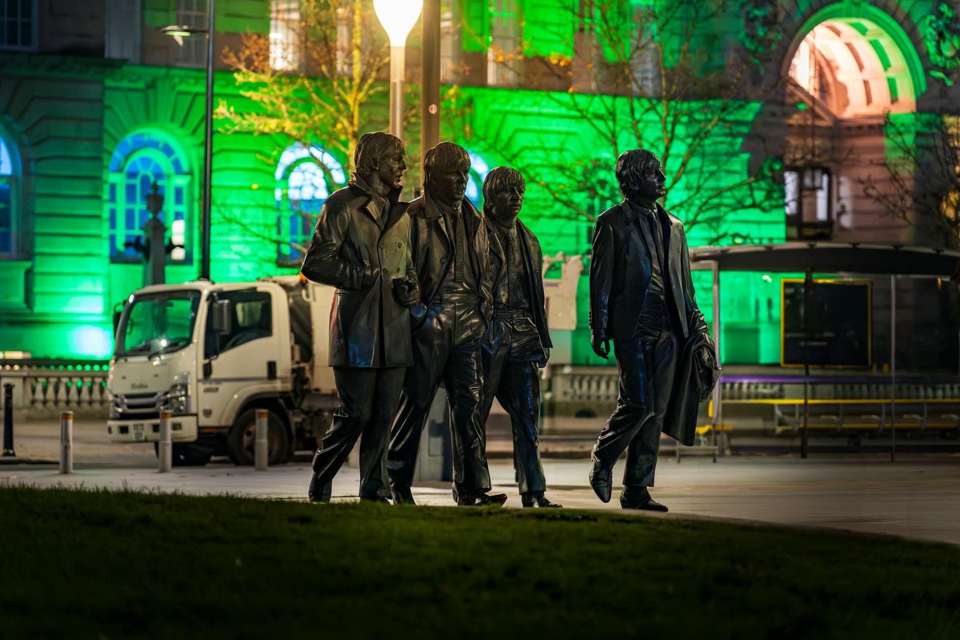 The four Beatles statues at Liverpool Pier Head, lit up at night
