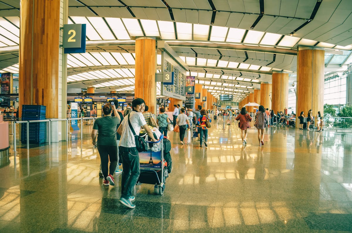 Travellers walking through a busy international airport terminal during the peak summer holiday season