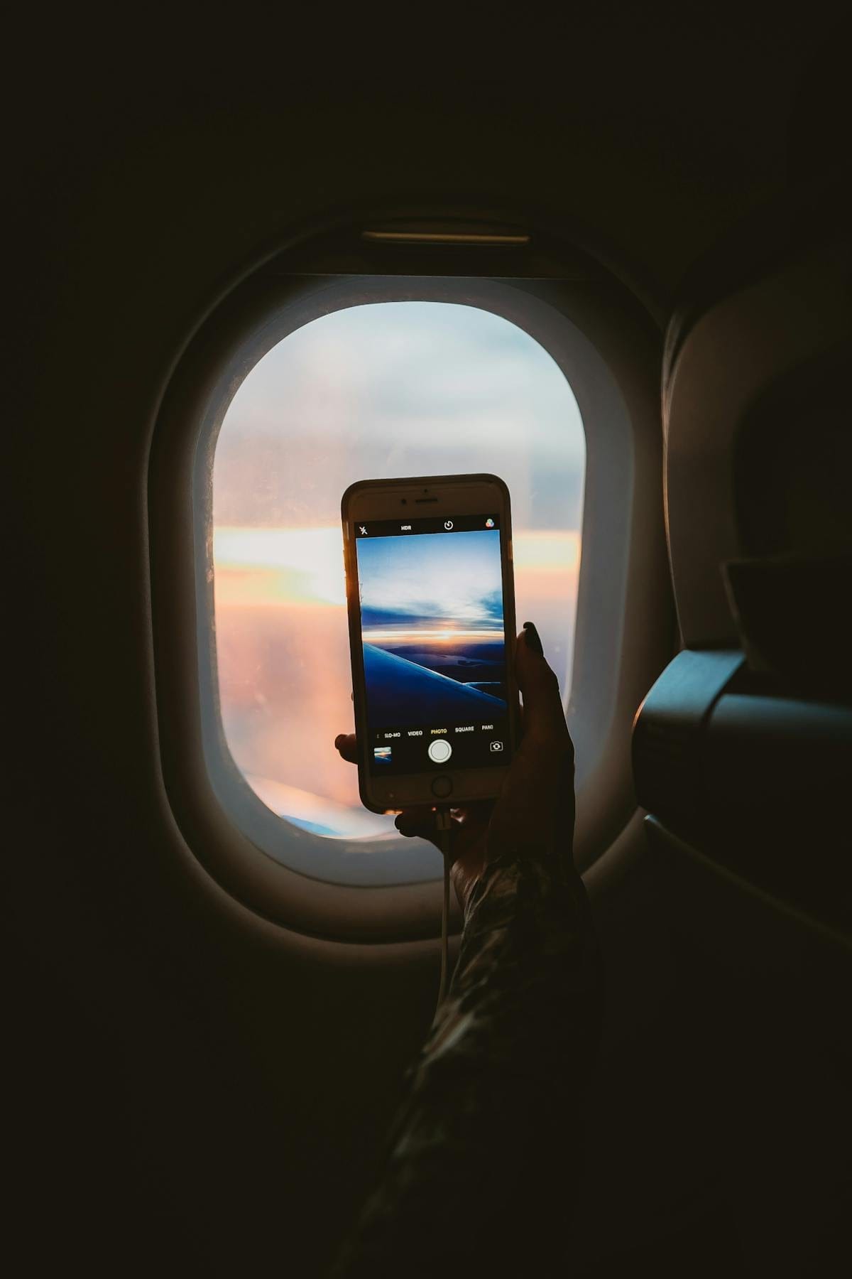 Person holding smartphone inside an airplane cabin while in flight