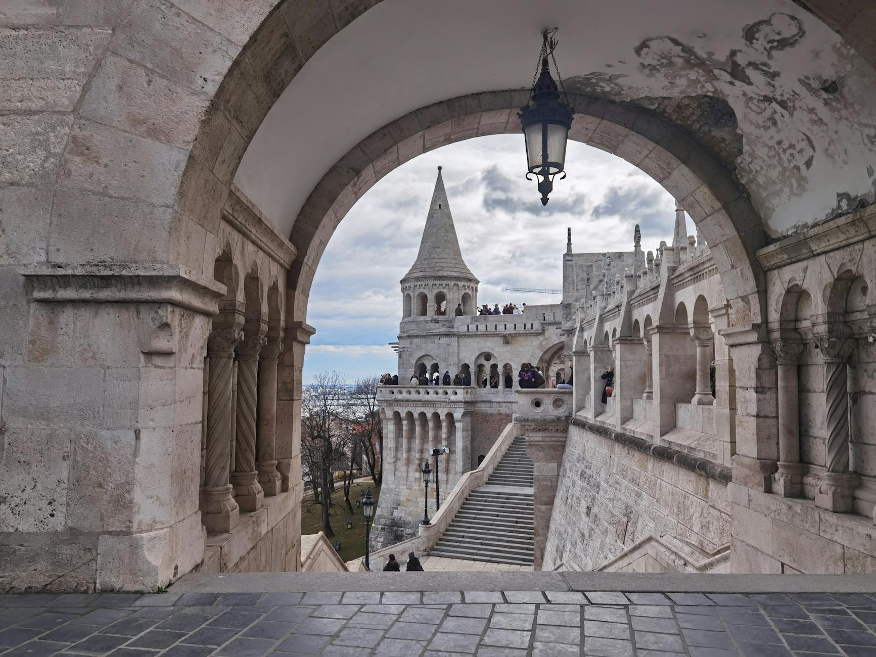 The white turrets of Fisherman's Bastion viewed through a stone arch in Budapest.