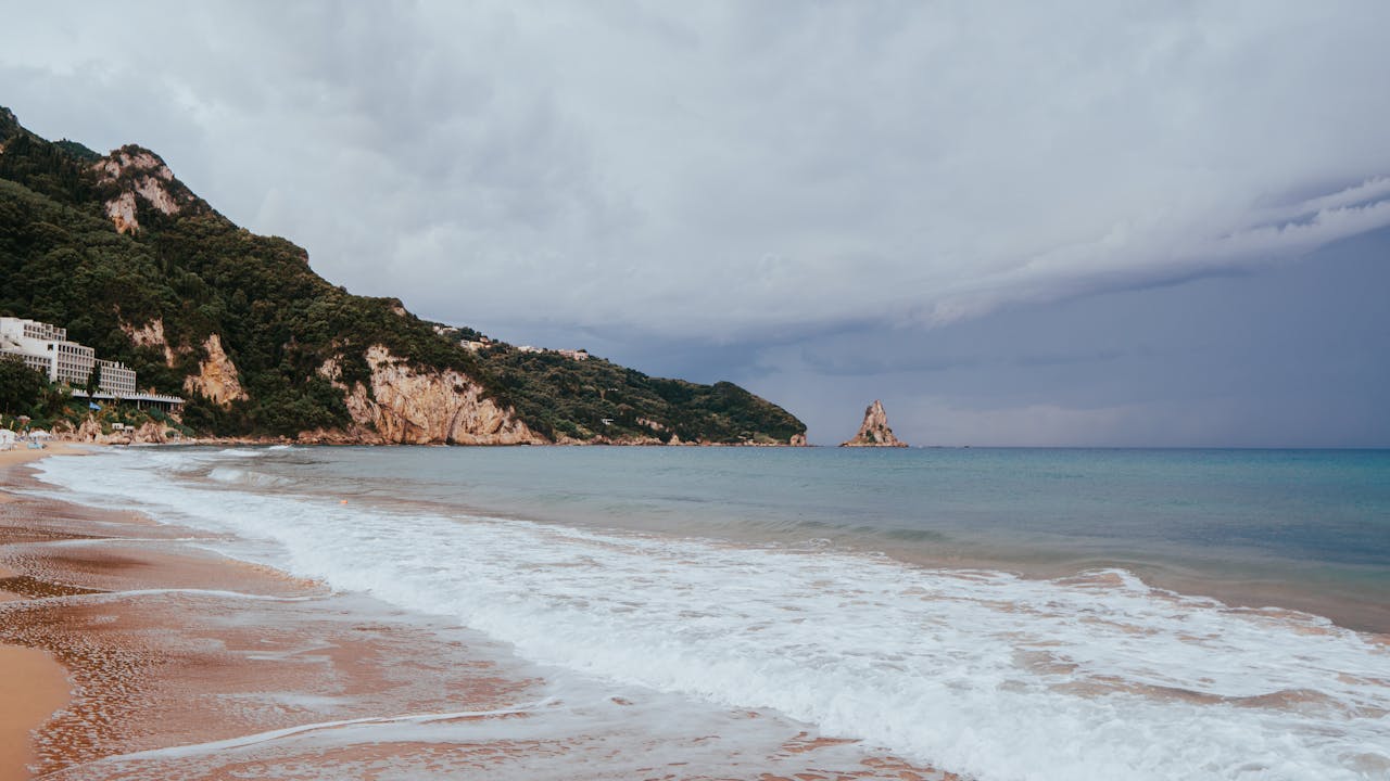 Clear turquoise water and golden sand at a beach in Corfu, Greece, in summer