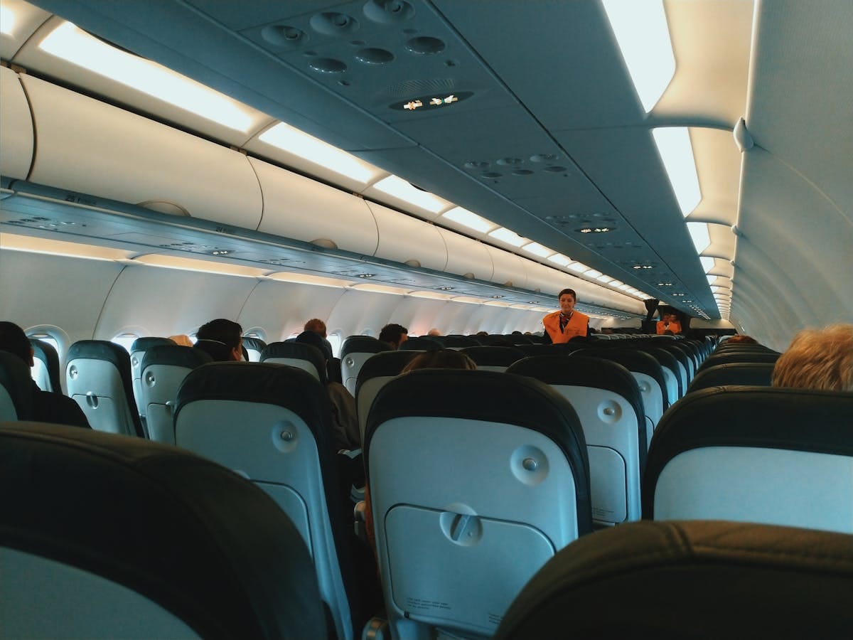 Interior of a commercial airplane cabin showing rows of seats and overhead storage compartments