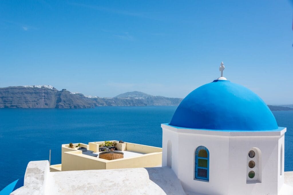 Blue-domed church in Santorini, Greece, overlooking the caldera and Aegean Sea in July