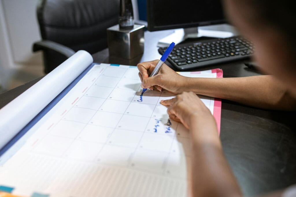 Woman writing on a large desk calendar in an office, planning days off work