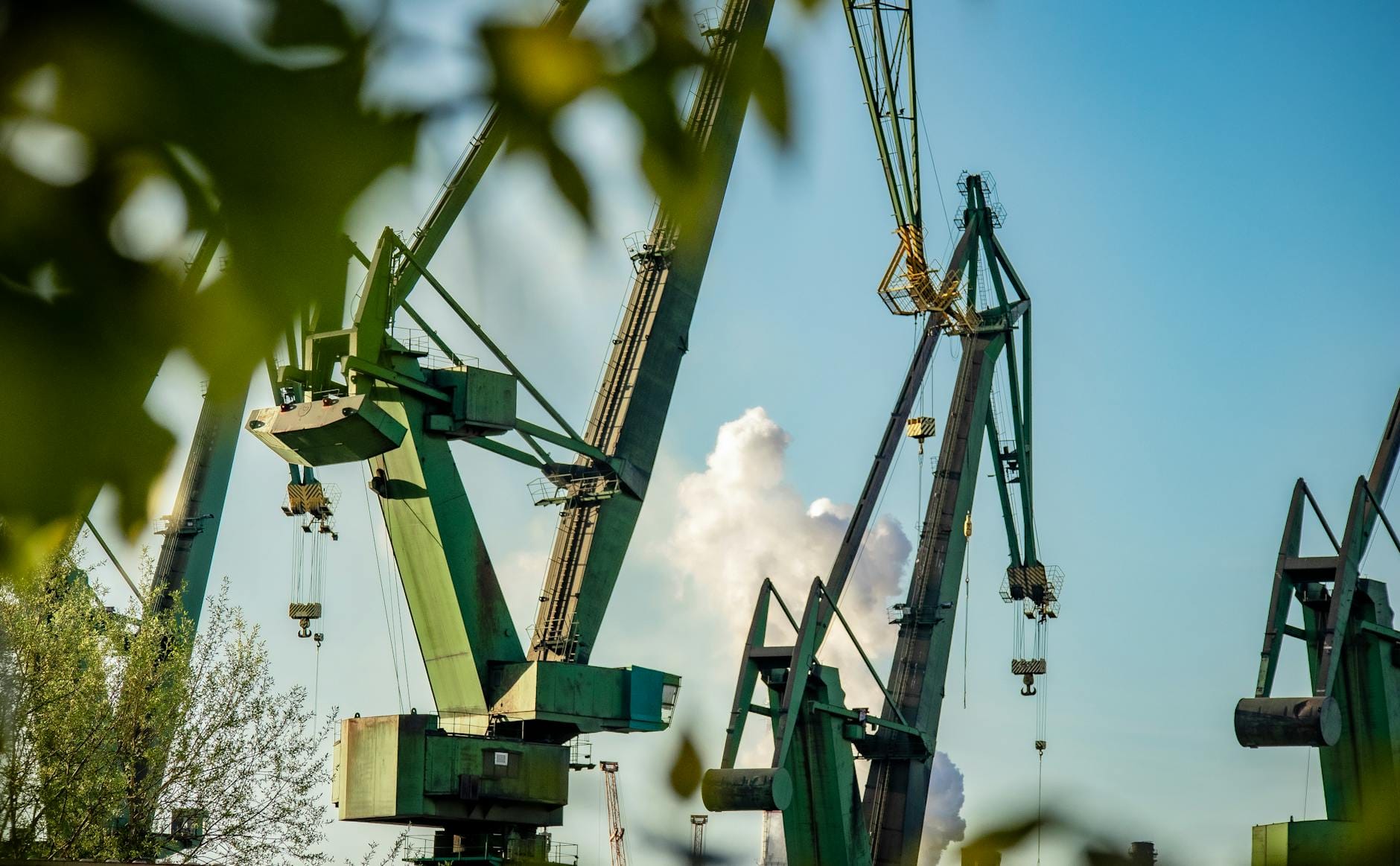 Green industrial cranes at the historic Gdansk Shipyard against a blue sky