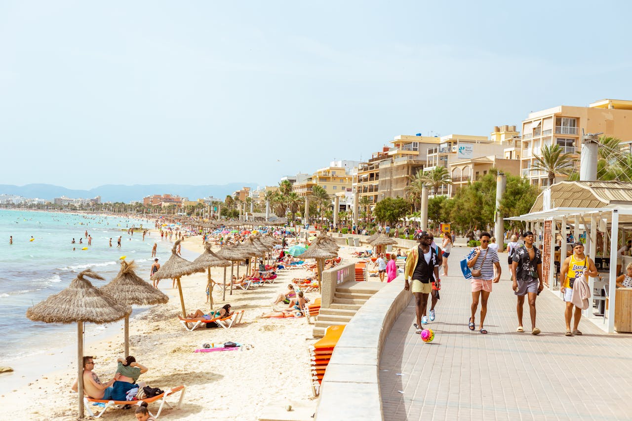 Sunbathers on a beach in Ibiza, Spain, with clear turquoise water in July