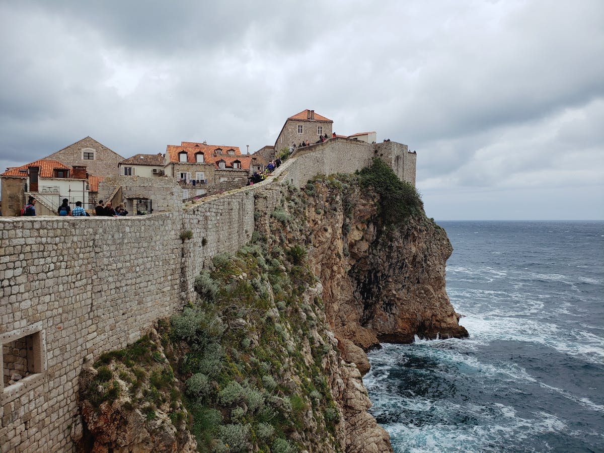 Historic city walls of Dubrovnik perched above the clear blue Adriatic sea, Croatia