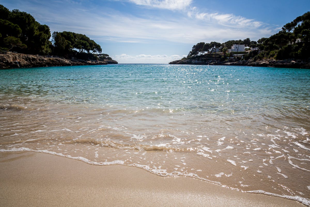 Peaceful coastal cove with clear turquoise water and gentle waves in Mallorca, Spain