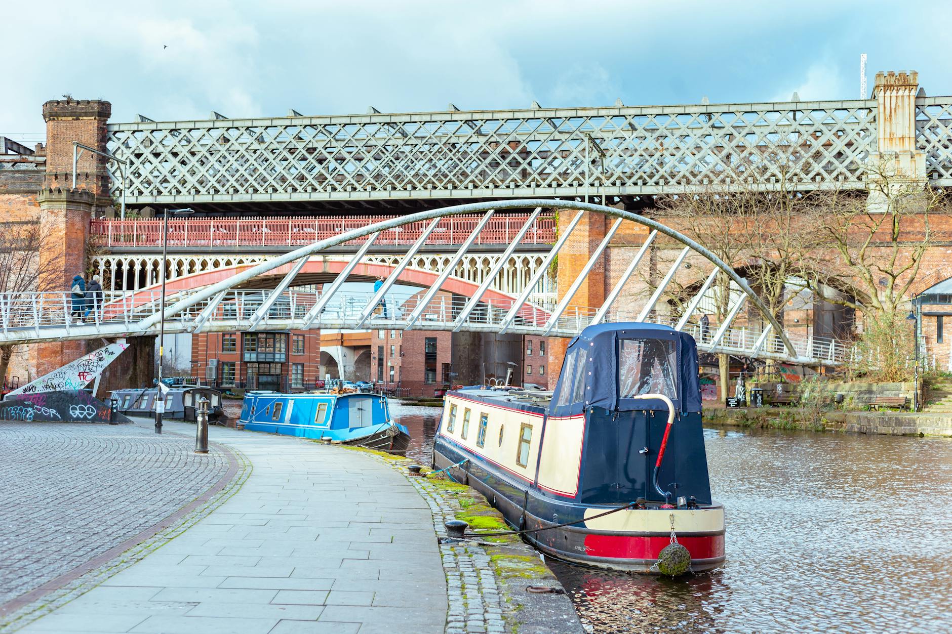 A narrowboat on the canal at Castlefield, Manchester, beside a historic iron footbridge