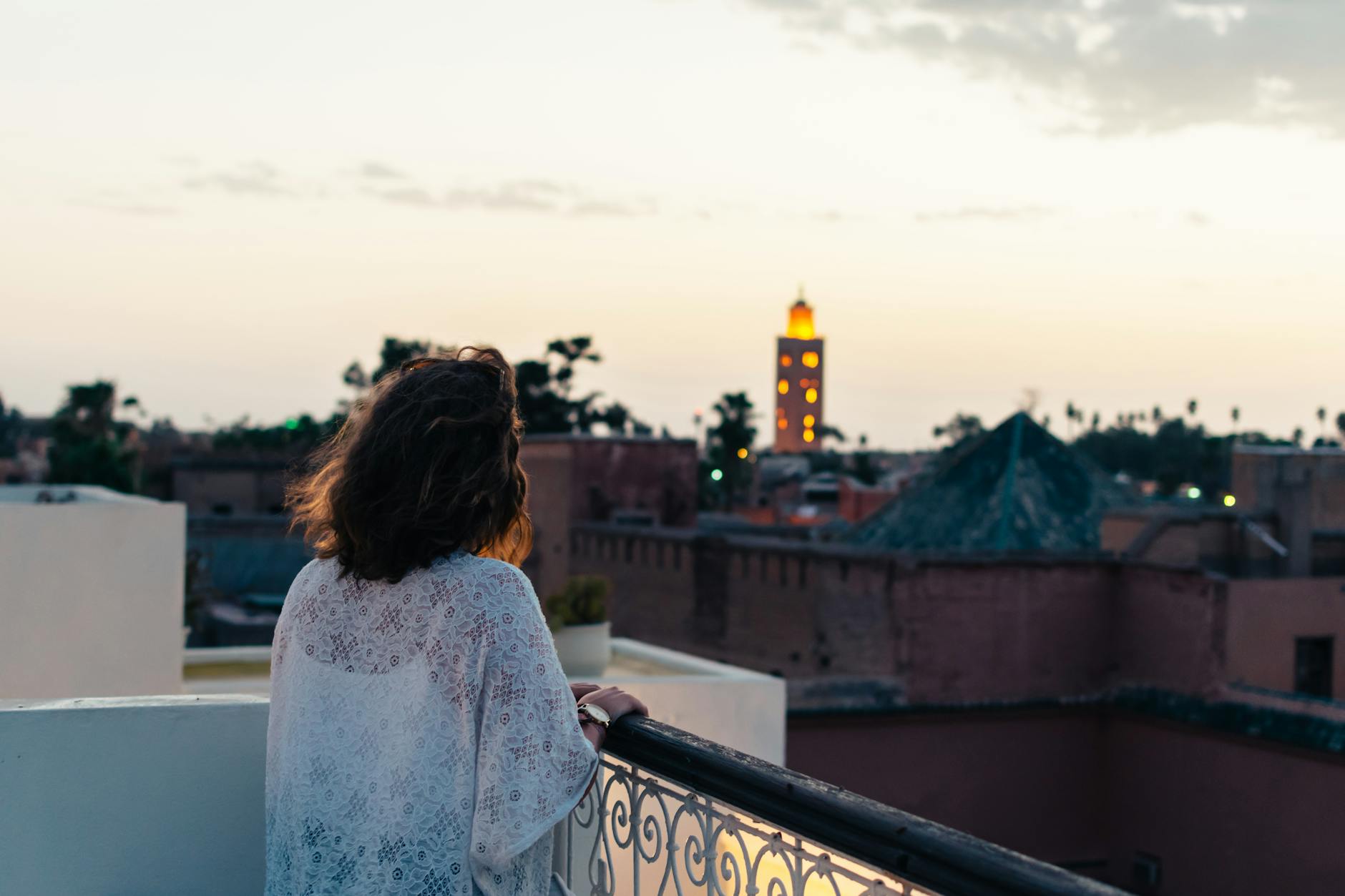 Woman viewing Marrakech skyline with Koutoubia Mosque at dusk