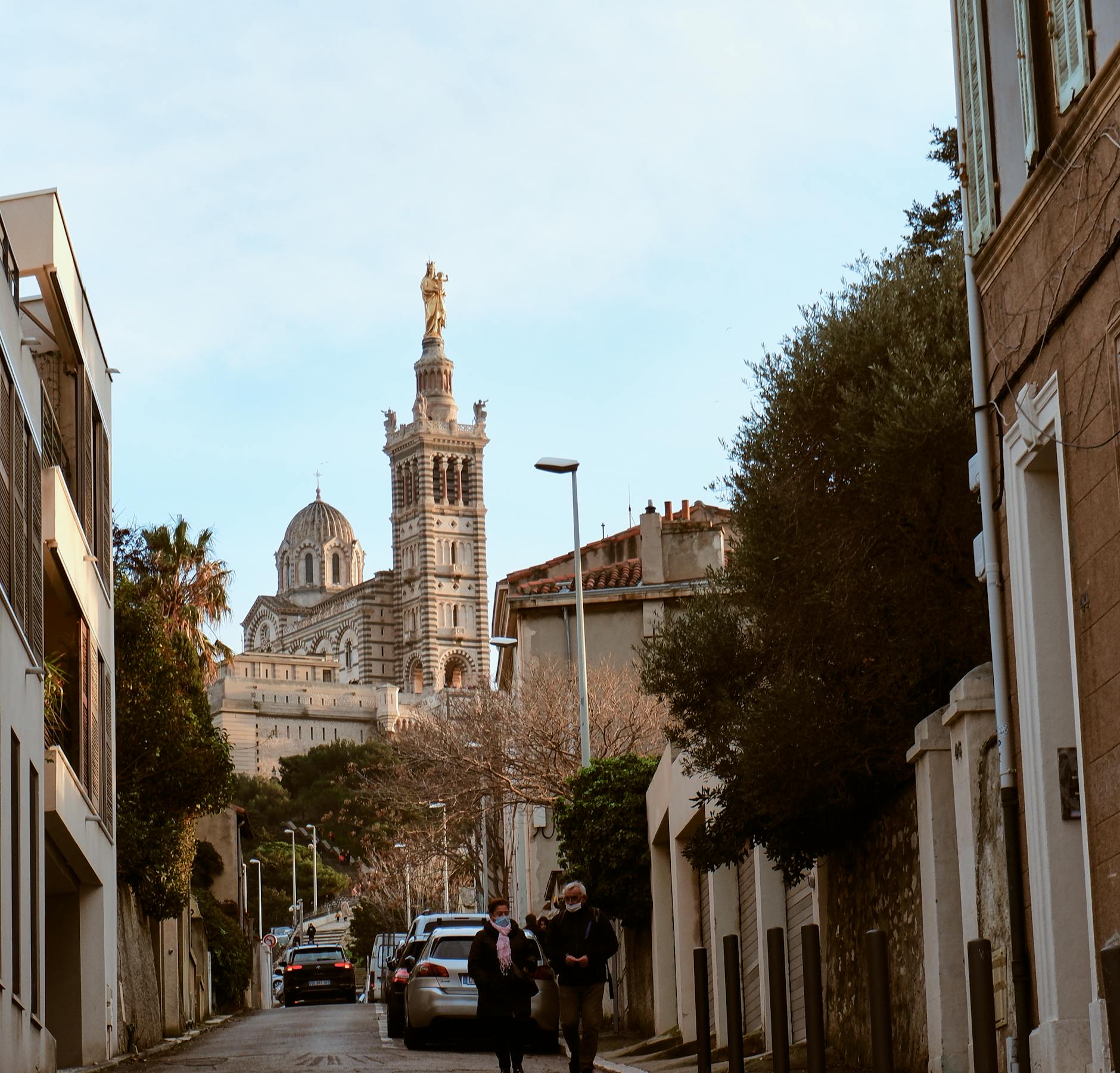Street scene in Marseille with Notre-Dame de la Garde visible in the background.