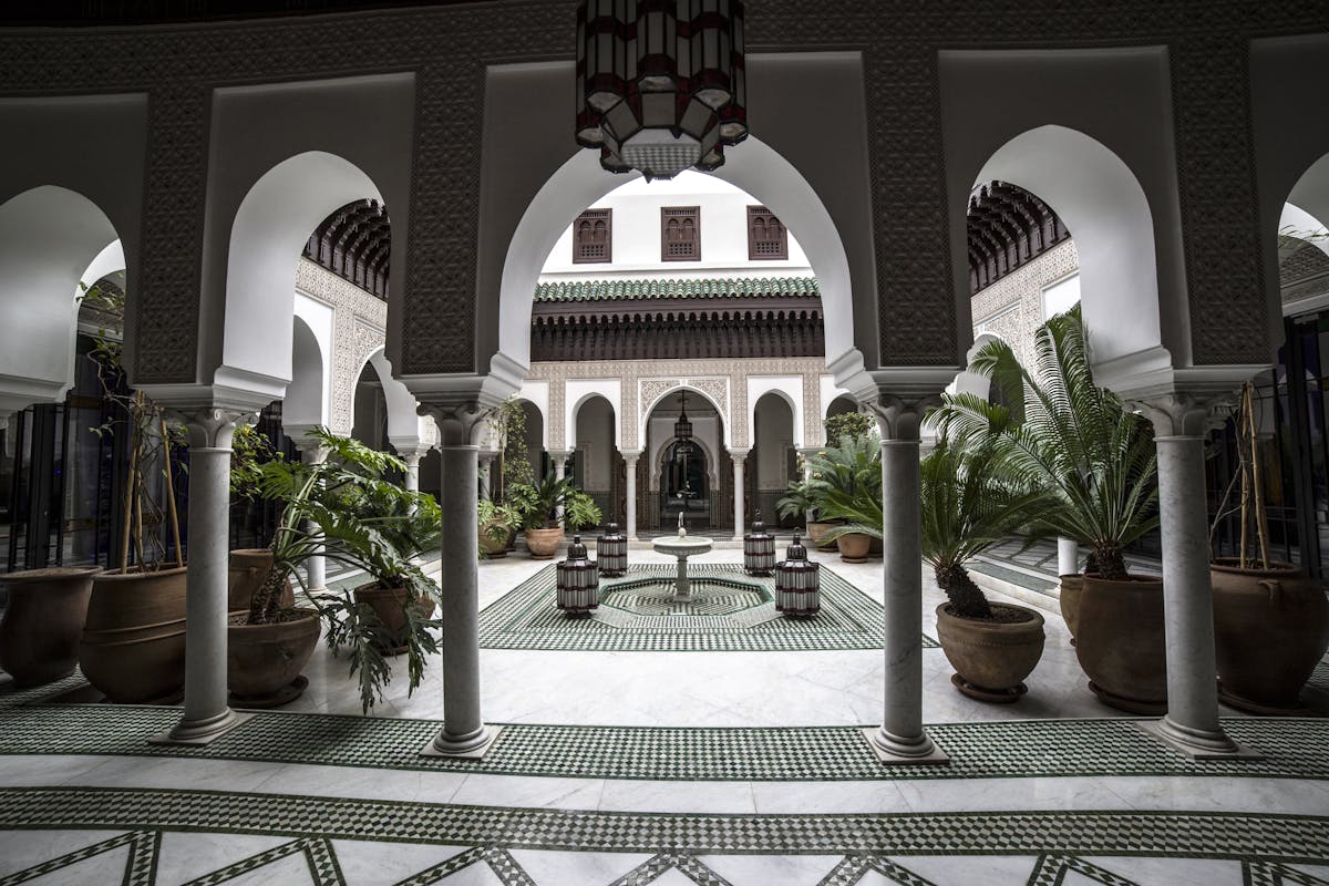 Courtyard of a traditional Moroccan riad with arches, columns and a central fountain.