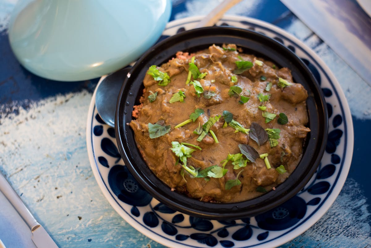 Moroccan tagine garnished with fresh herbs, a budget-friendly local meal.