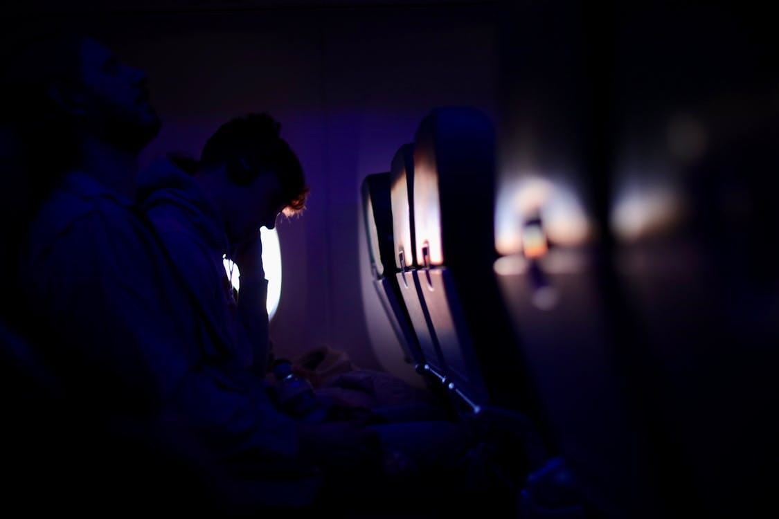 Passengers resting in an aircraft cabin with ambient lighting