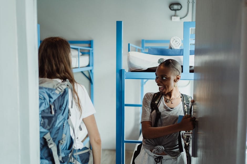Two women with backpacks arriving at a hostel with bunk beds