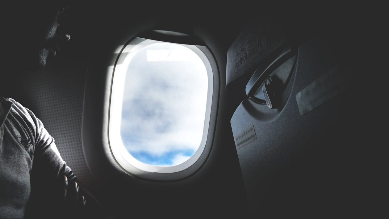 Passenger looking through an aircraft window at clouds during a flight