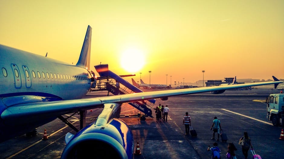 Passengers boarding an airplane at sunrise on an airport tarmac