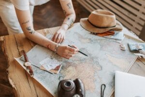 Woman planning a trip with a world map, passport and travel essentials on a table