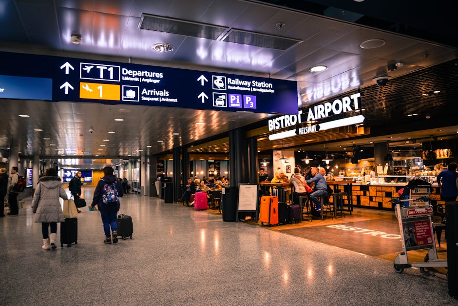 Travellers walking through a busy airport terminal with luggage