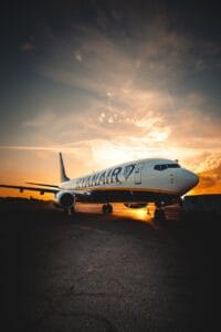 white passenger plane parked on a ramp under golden sky