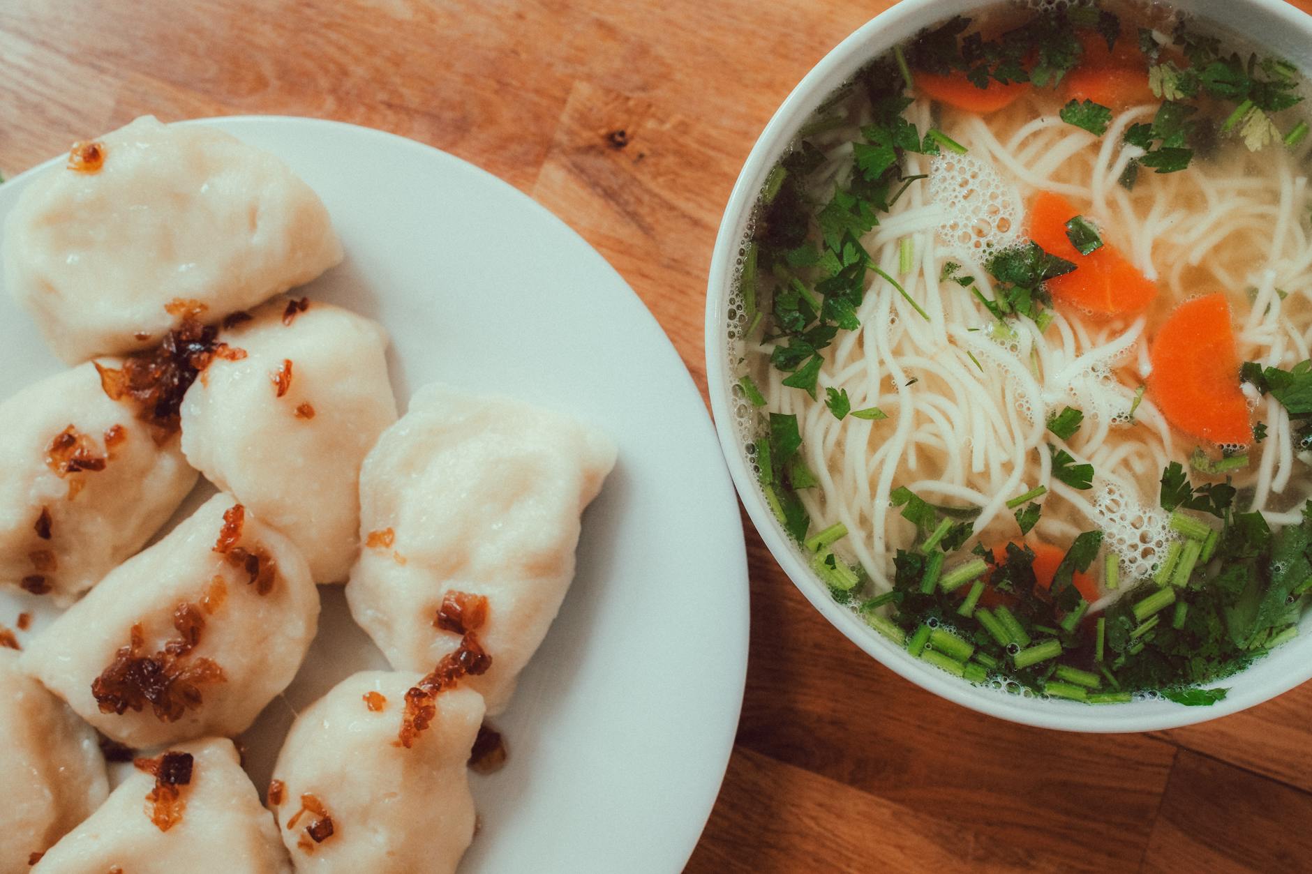 Traditional Polish pierogi dumplings served with fried onions and soup