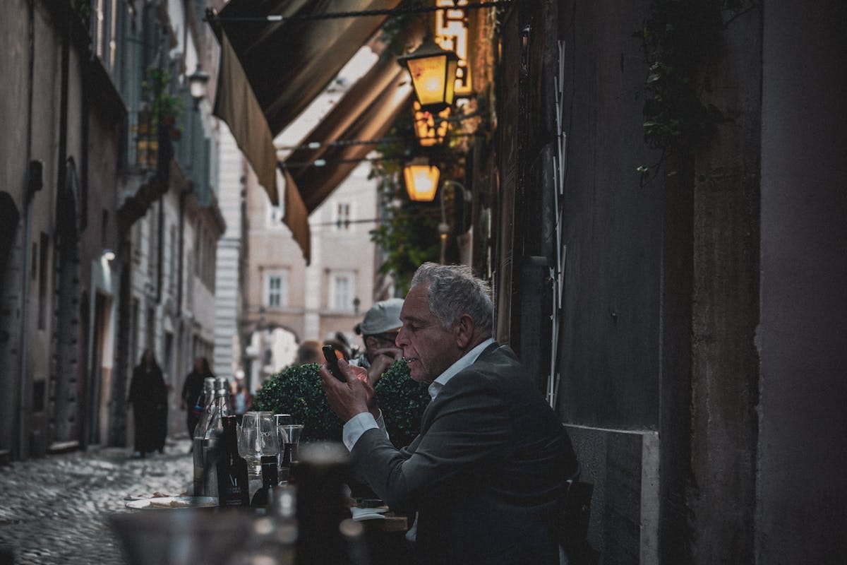 Evening outdoor dining scene on a Rome street, warm lamplights, people eating at tables