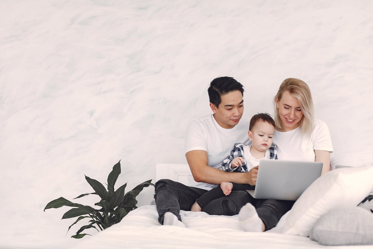 A couple with their child looking at a laptop screen while planning a school holiday hotel booking