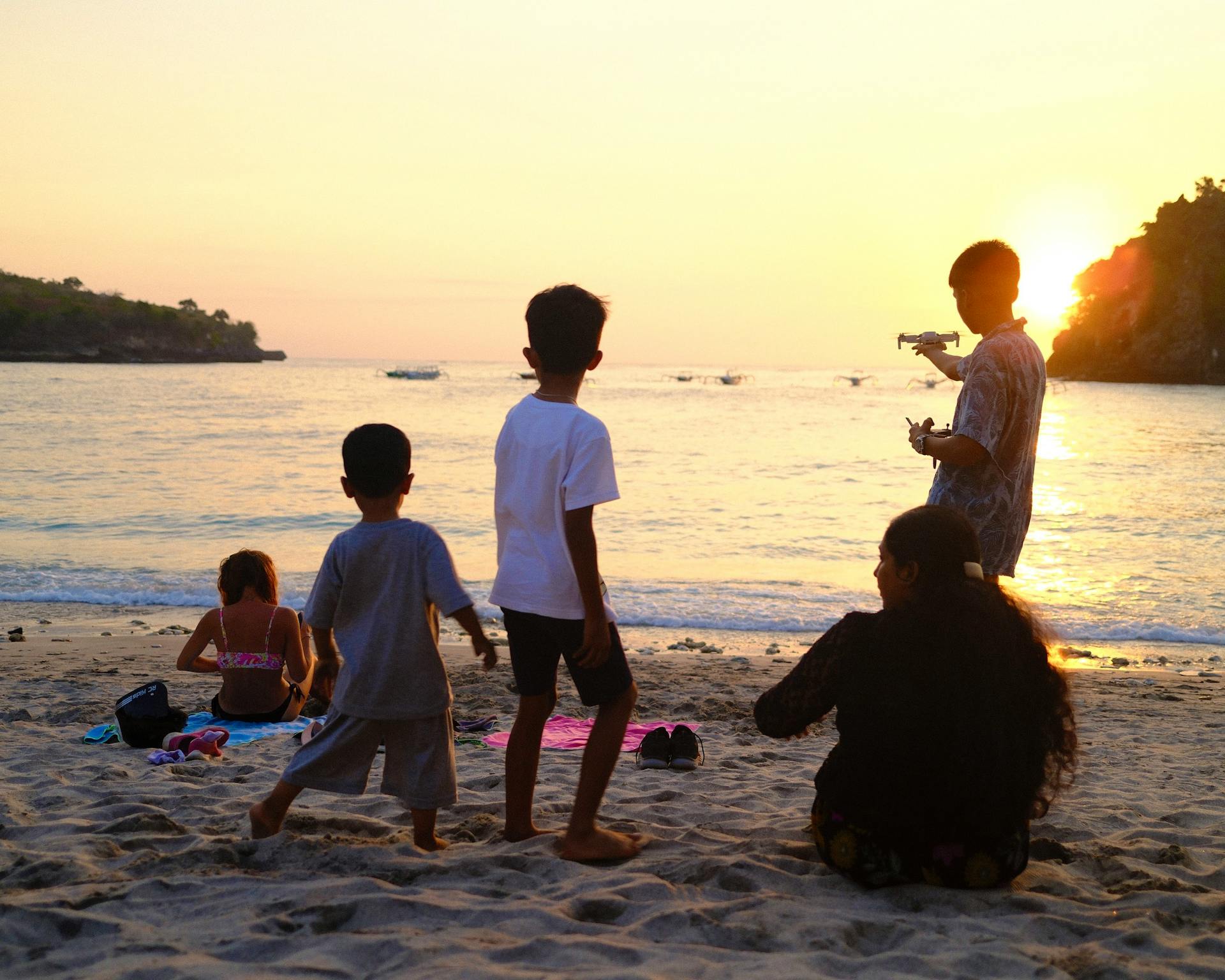 Family watching a sunset on the beach, with children playing at the water's edge