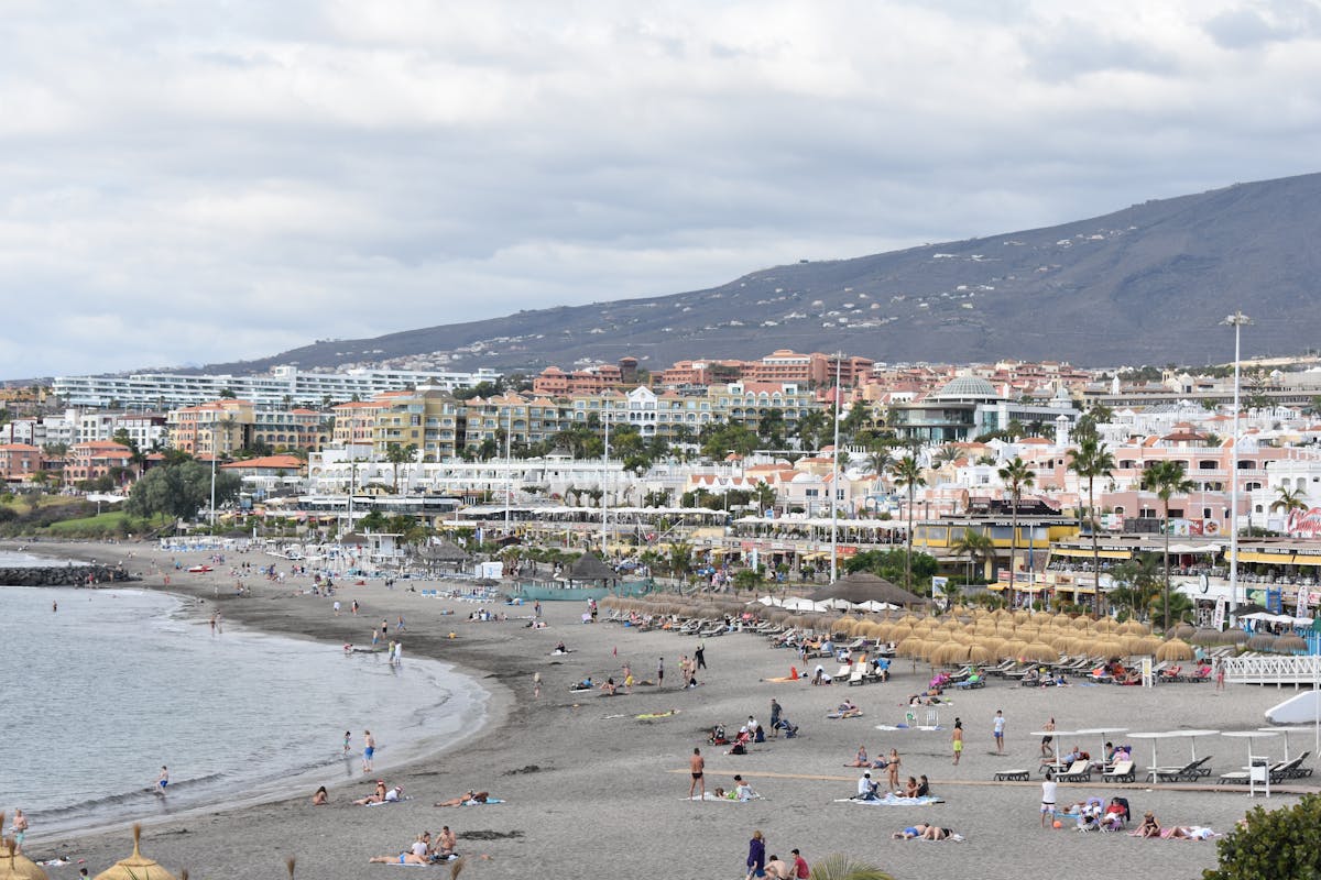 Beach scene at Playa de Fanabe in Costa Adeje, Tenerife, with sunbeds and clear blue sea
