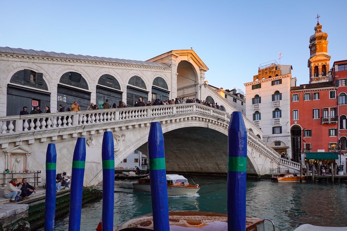 Rialto Bridge in Venice at daytime with tourists and market stalls along the canal bank