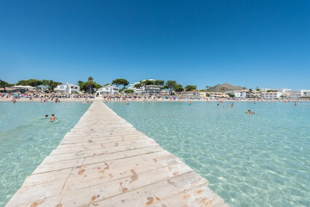 Alcudia beach in Majorca with clear water and a wooden pier