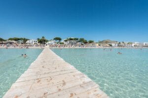 Alcudia beach in Majorca with clear water and a wooden pier