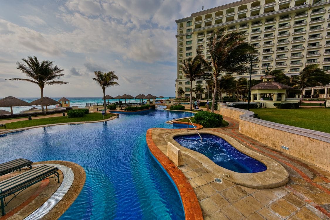 Tropical resort swimming pool with palm trees and ocean views at a Cancún hotel, Mexico