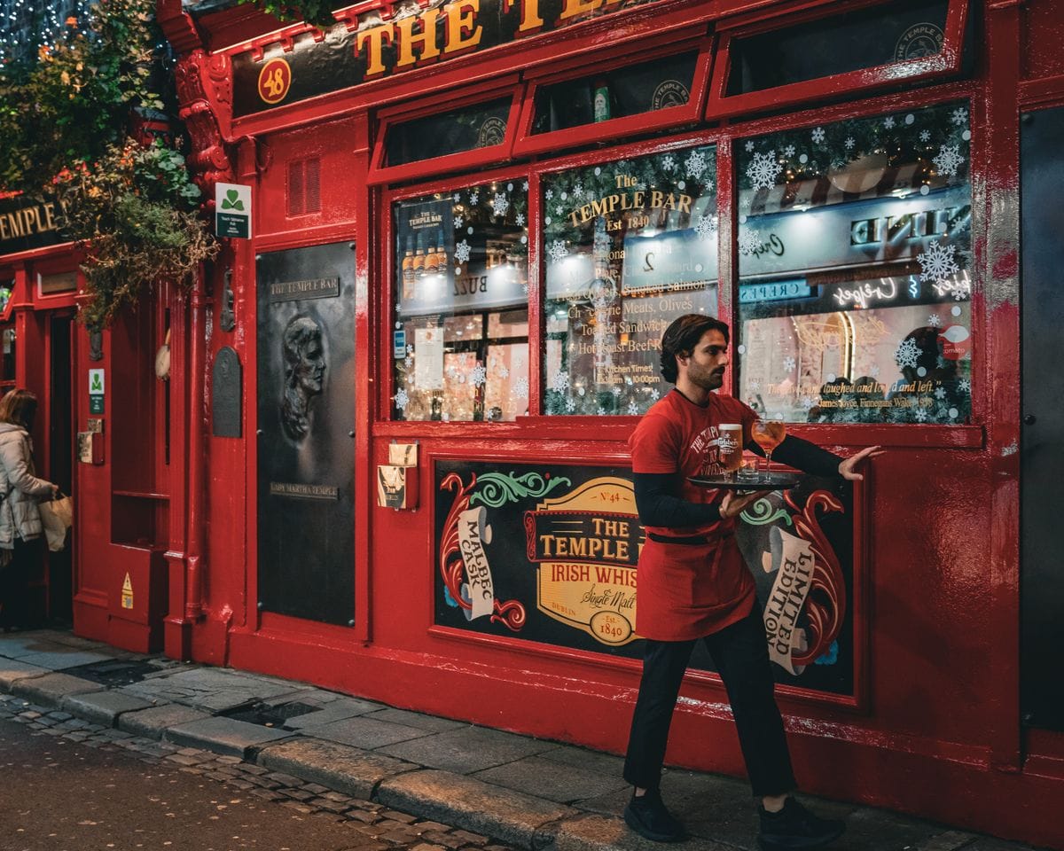A waiter carrying a tray on the cobbled street outside a Temple Bar pub in Dublin