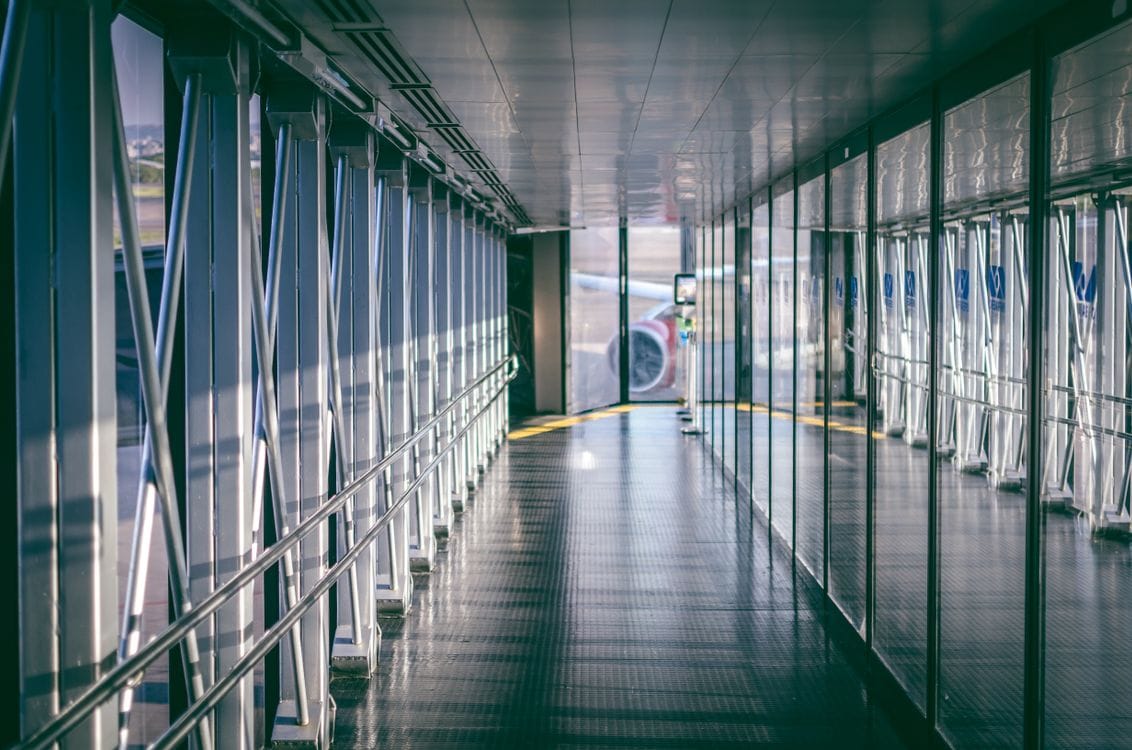 Airport jet bridge corridor with glass windows leading from gate to aircraft