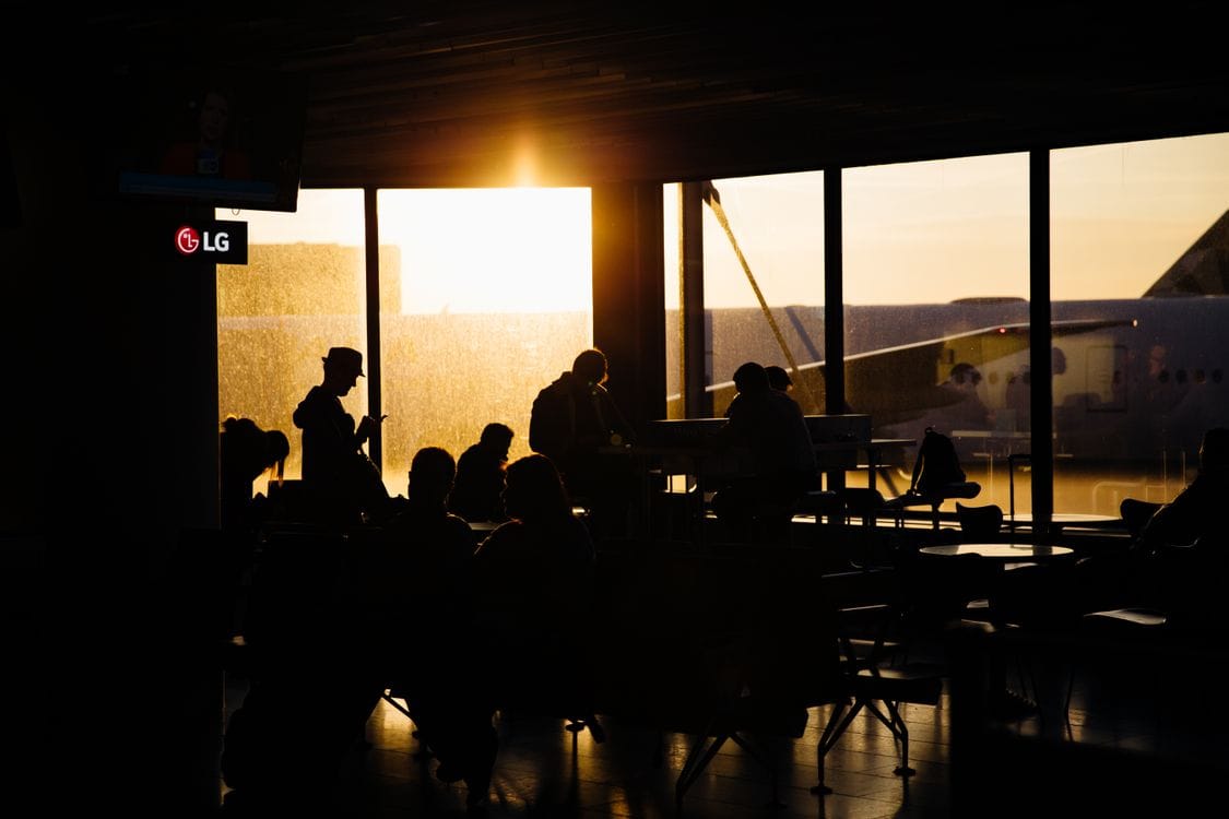 Travellers silhouetted against bright windows in an airport terminal