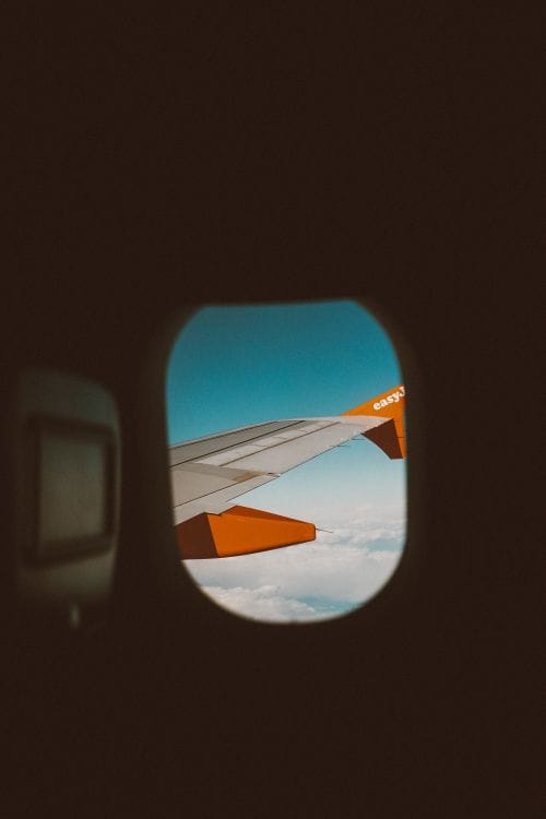 View from a window seat inside an easyJet aircraft showing the orange winglet against blue sky