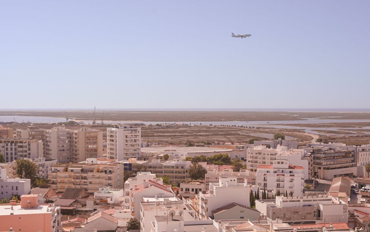 Aerial view of Faro city in Portugal with an aircraft flying overhead