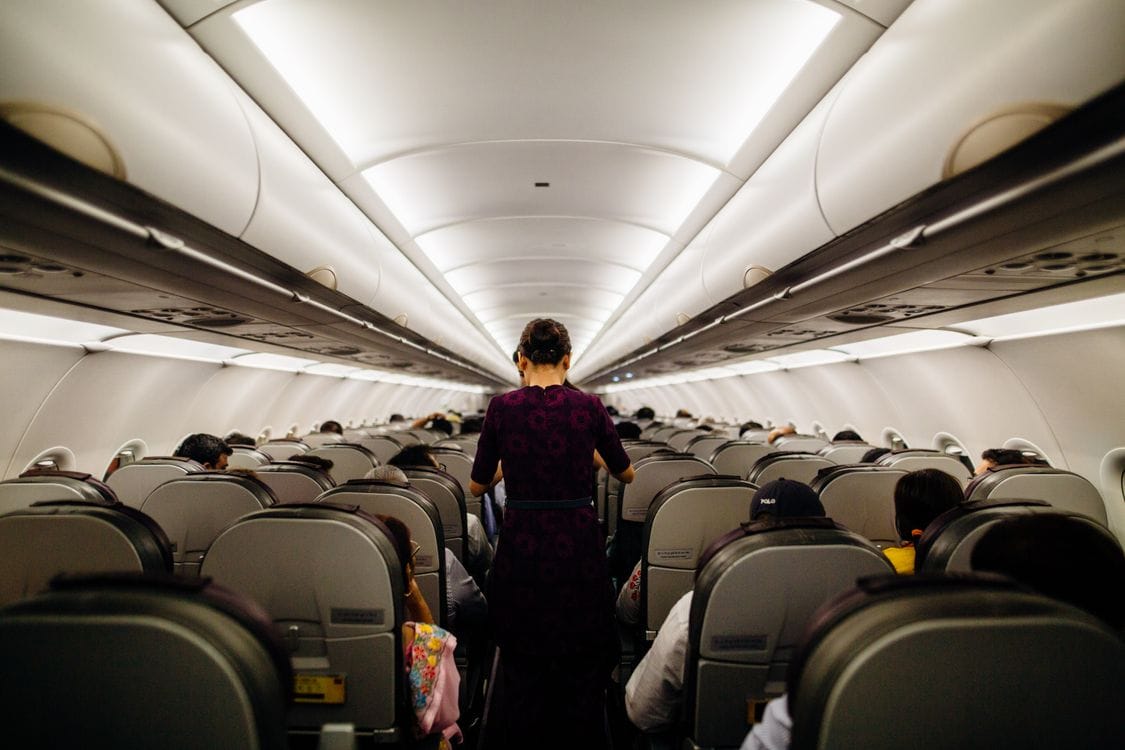 Flight attendant serving passengers in airplane cabin aisle