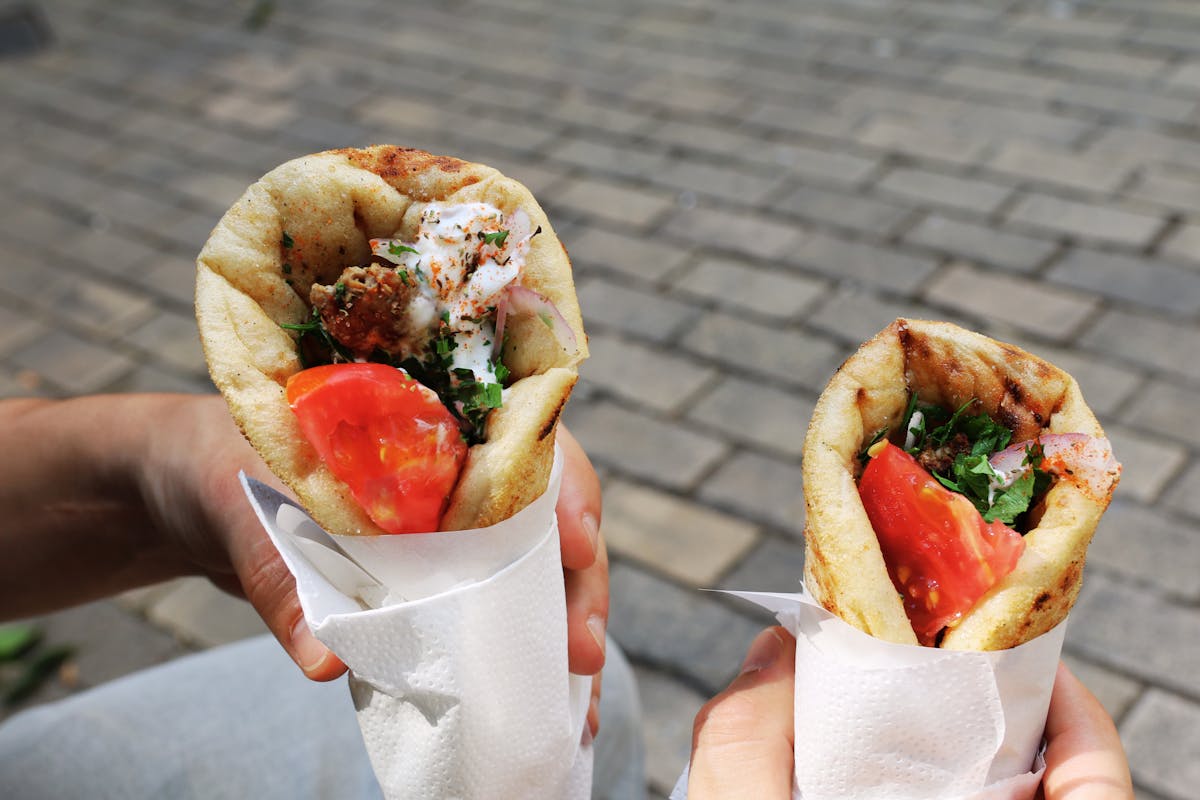 Two Greek gyros wraps held up, a classic budget street food