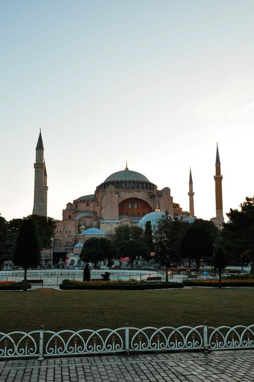 Hagia Sophia at sunset in Istanbul, showing the great domed mosque with minarets against an orange sky