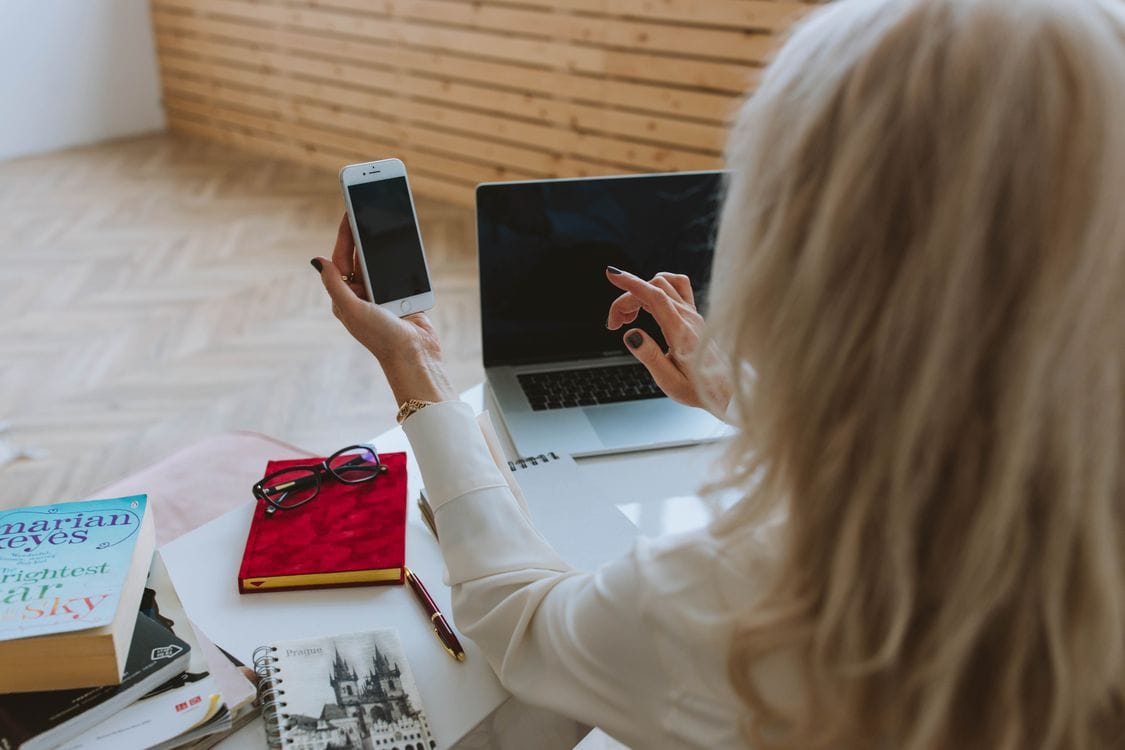 Woman comparing hotel rates on smartphone and laptop