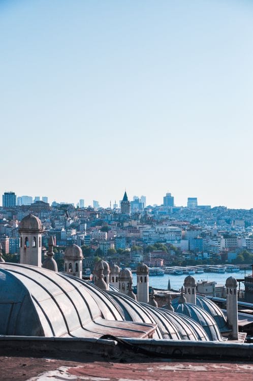 Rooftop view over Istanbul showing Ottoman mosque domes in the foreground with the city skyline beyond