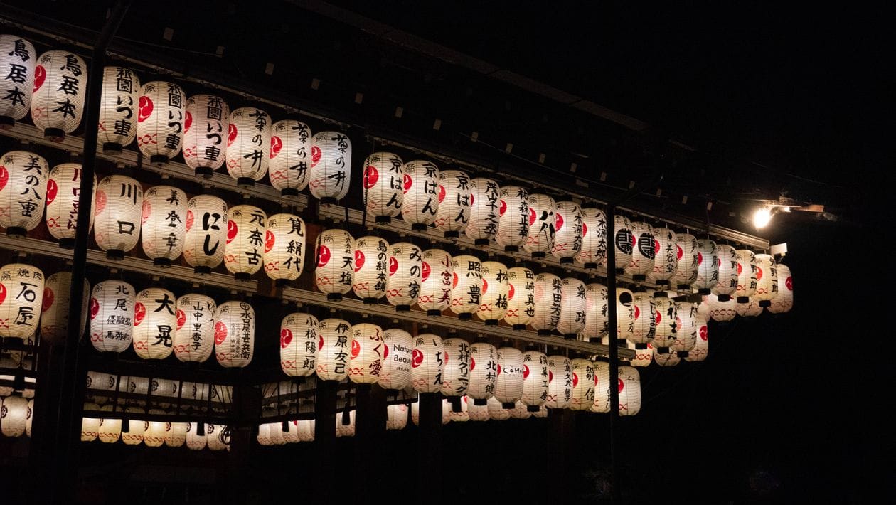 Rows of traditional paper lanterns lit up at night in Kyoto
