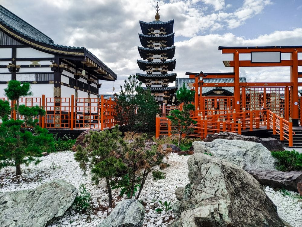 Traditional Japanese pagoda reflected in a pond surrounded by pine trees