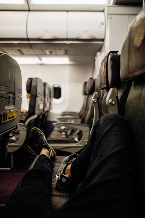 Passenger relaxing with legs stretched out in an economy class airplane seat